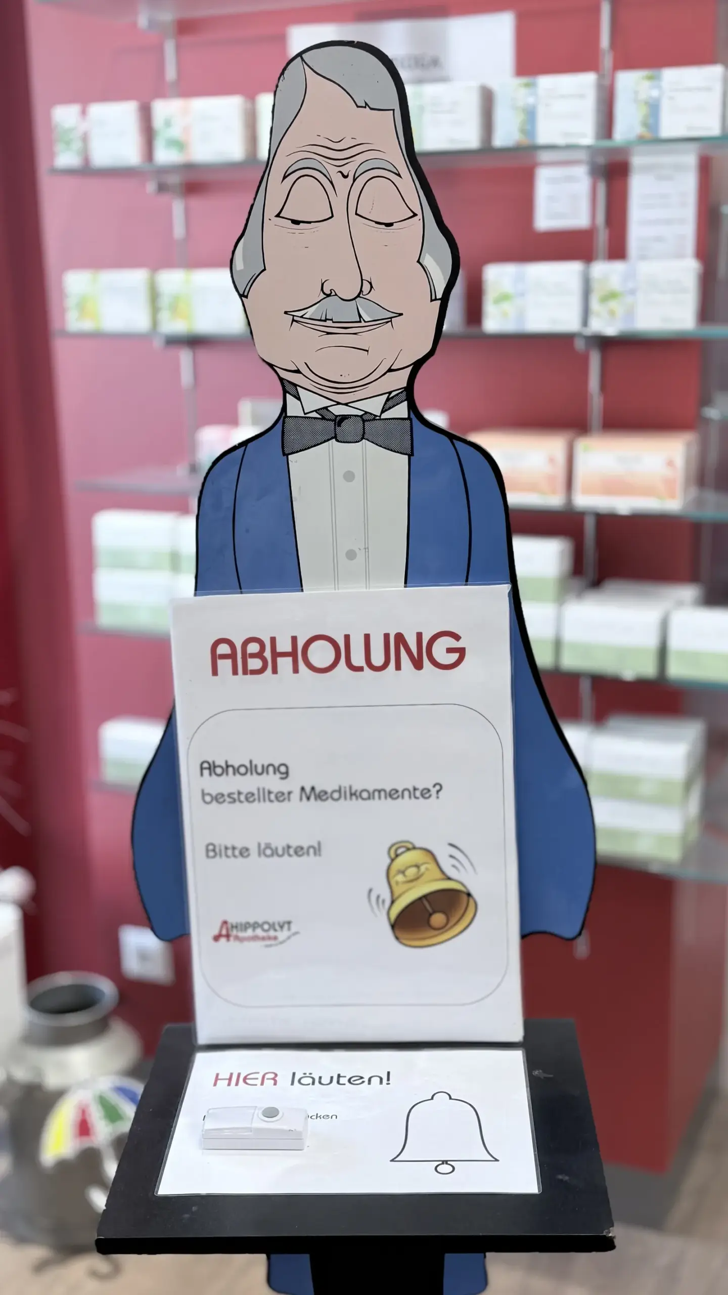 Abholtisch mit Glocke und Hinweisschild „Abholung bestellter Medikamente“