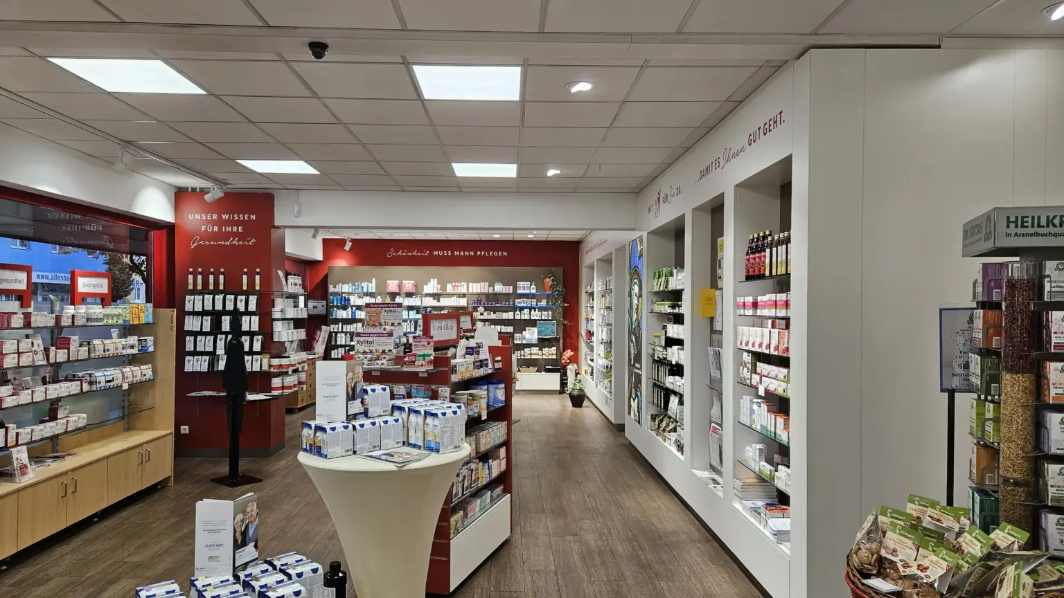 Helle Offizin der Hippolyt-Apotheke mit Regalen, rotem Beratungsbereich und dem Schriftzug „Damit es Ihnen gut geht“