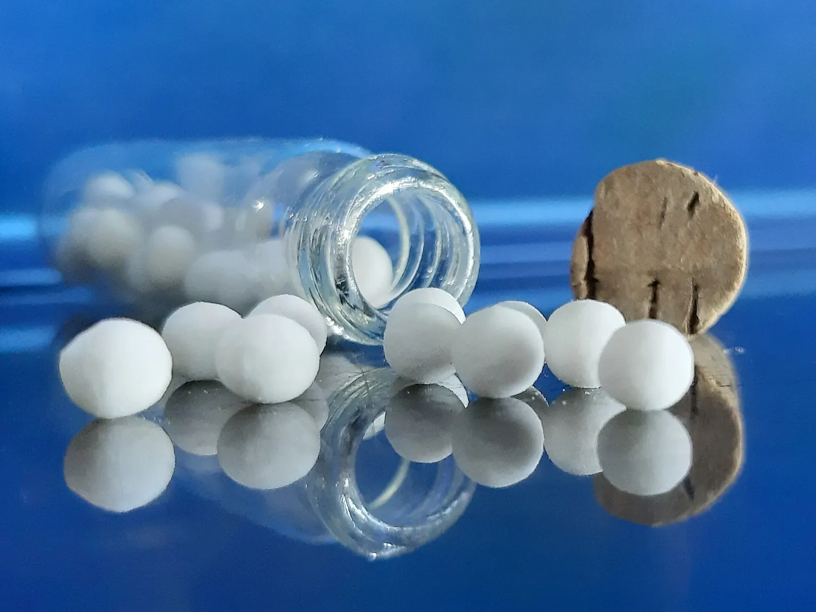 Homöopathische Globuli neben einem Glasfläschchen