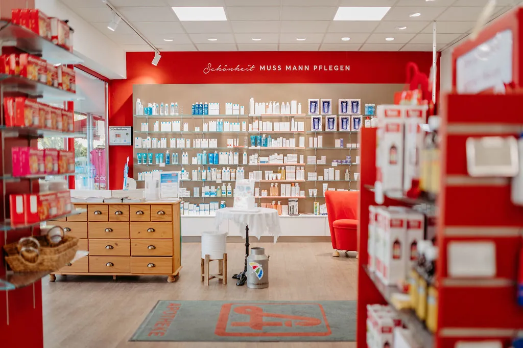 Verkaufsraum der Hippolyt-Apotheke mit roten Regalen und Holzmöbeln